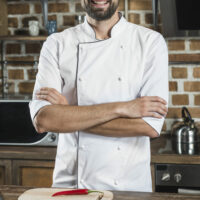 gros-plan-male-chef-bras-croises-debout-derriere-cuisine-compteur